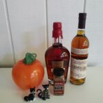 Maker’s Mark Private Select and Rowan’s Creek bourbon bottles alongside pumpkin pie spice, a blown-glass pumpkin by Glen Echo Glassworks, and two Murano glass cat figurines, arranged for a pumpkin-infused bourbon recipe.
