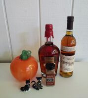 Maker’s Mark Private Select and Rowan’s Creek bourbon bottles alongside pumpkin pie spice, a blown-glass pumpkin by Glen Echo Glassworks, and two Murano glass cat figurines, arranged for a pumpkin-infused bourbon recipe.